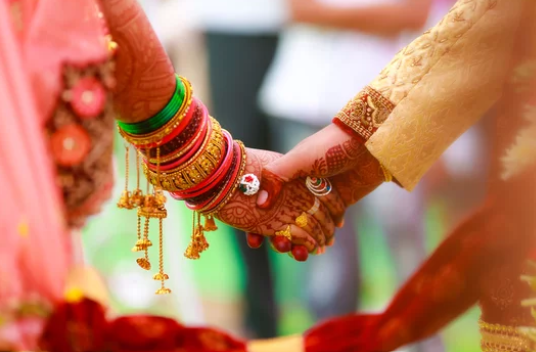 Bride and groom's hands adorned with mehendi and bangles